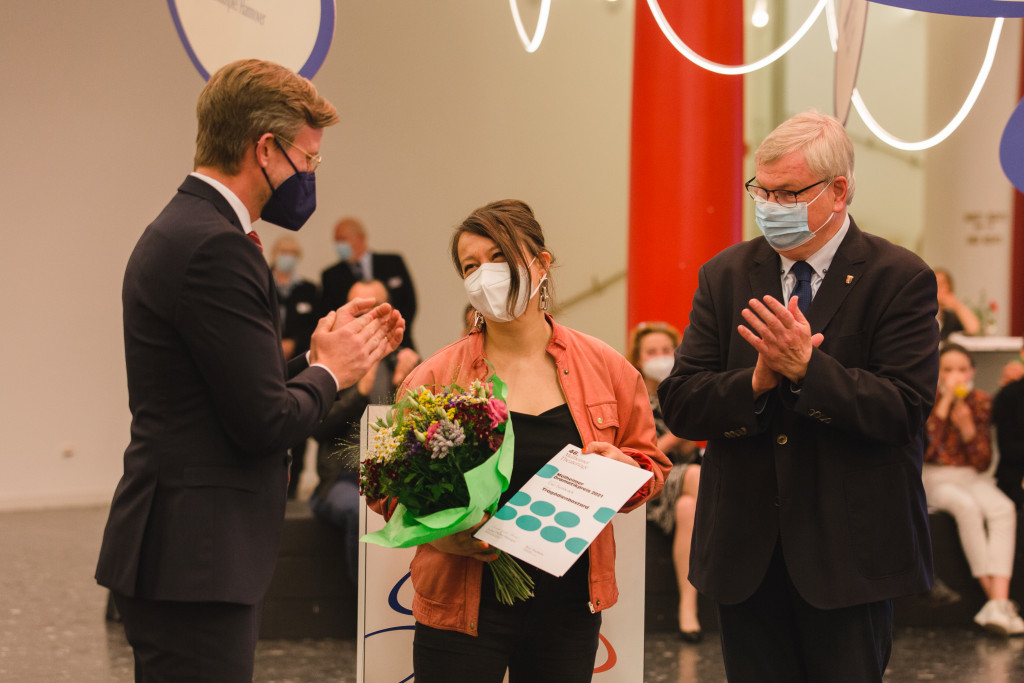 Bürgermeister Markus Püll (r.) und Staatssekretär Dr. Dirk Günnewig (l.) überreichen den Mülheimer Dramatikpreis 2021 an Ewe Benbenek / Foto: Daniela Motzkus